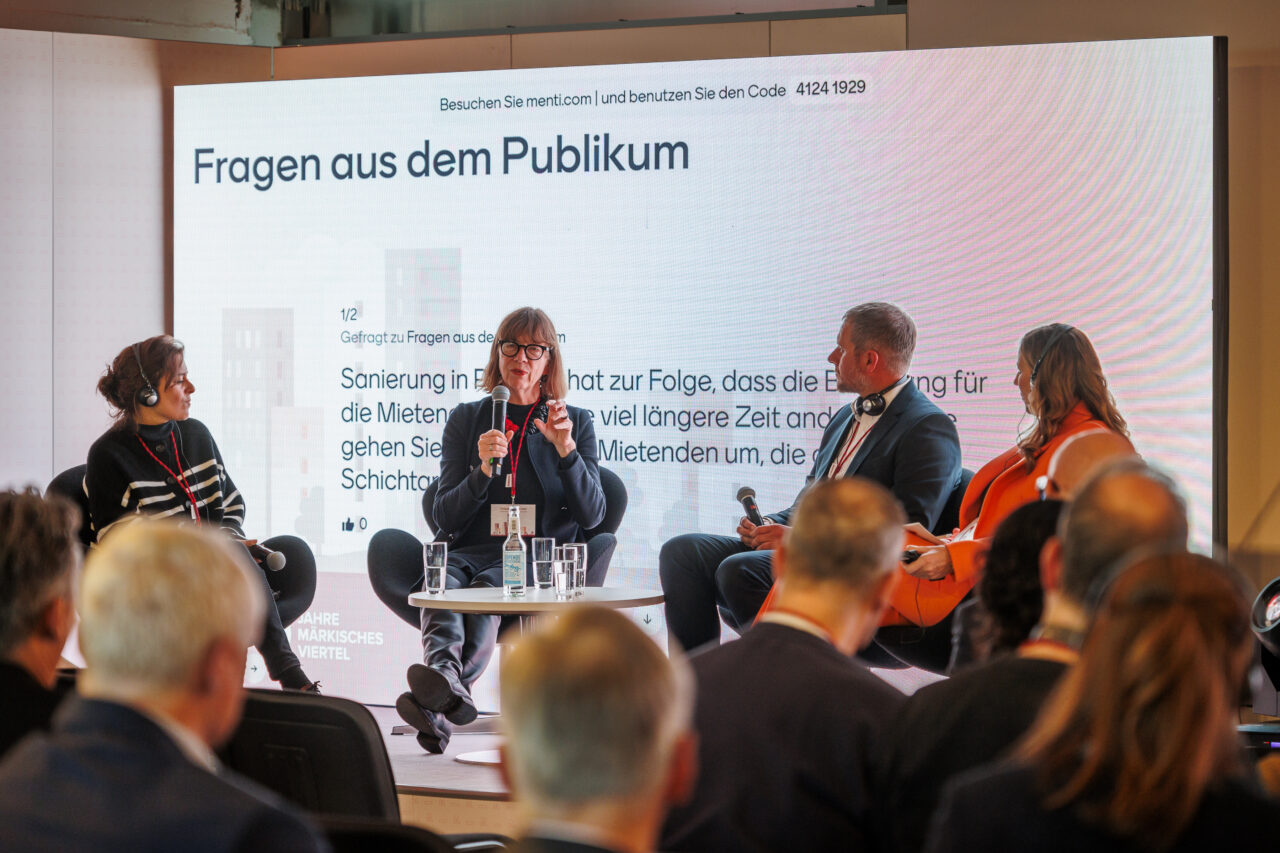 Menschen nehmen an einer Podiumsdiskussion zum Thema "Klima & Quartier" teil